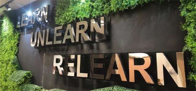 "Unlearn Relearn" acrylic lettering on a green wall — Acrylic Signage by Garrison Productions, Singapore